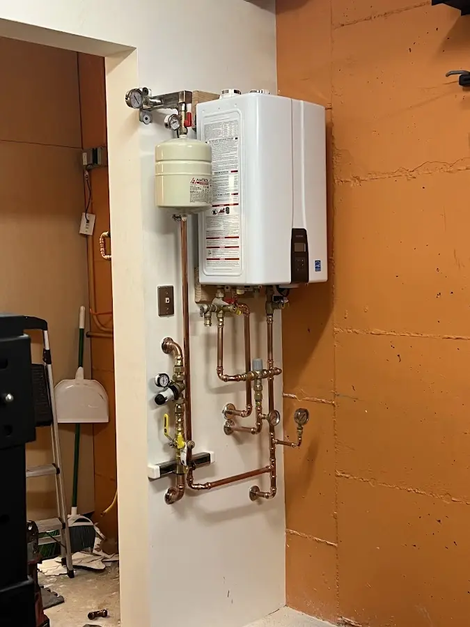 Plumbing technician inspecting water heater connections in Massillon